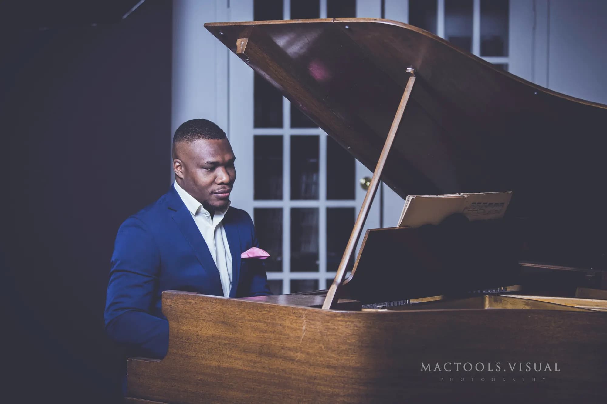 Maxwell AU in a navy suit playing a grand piano.