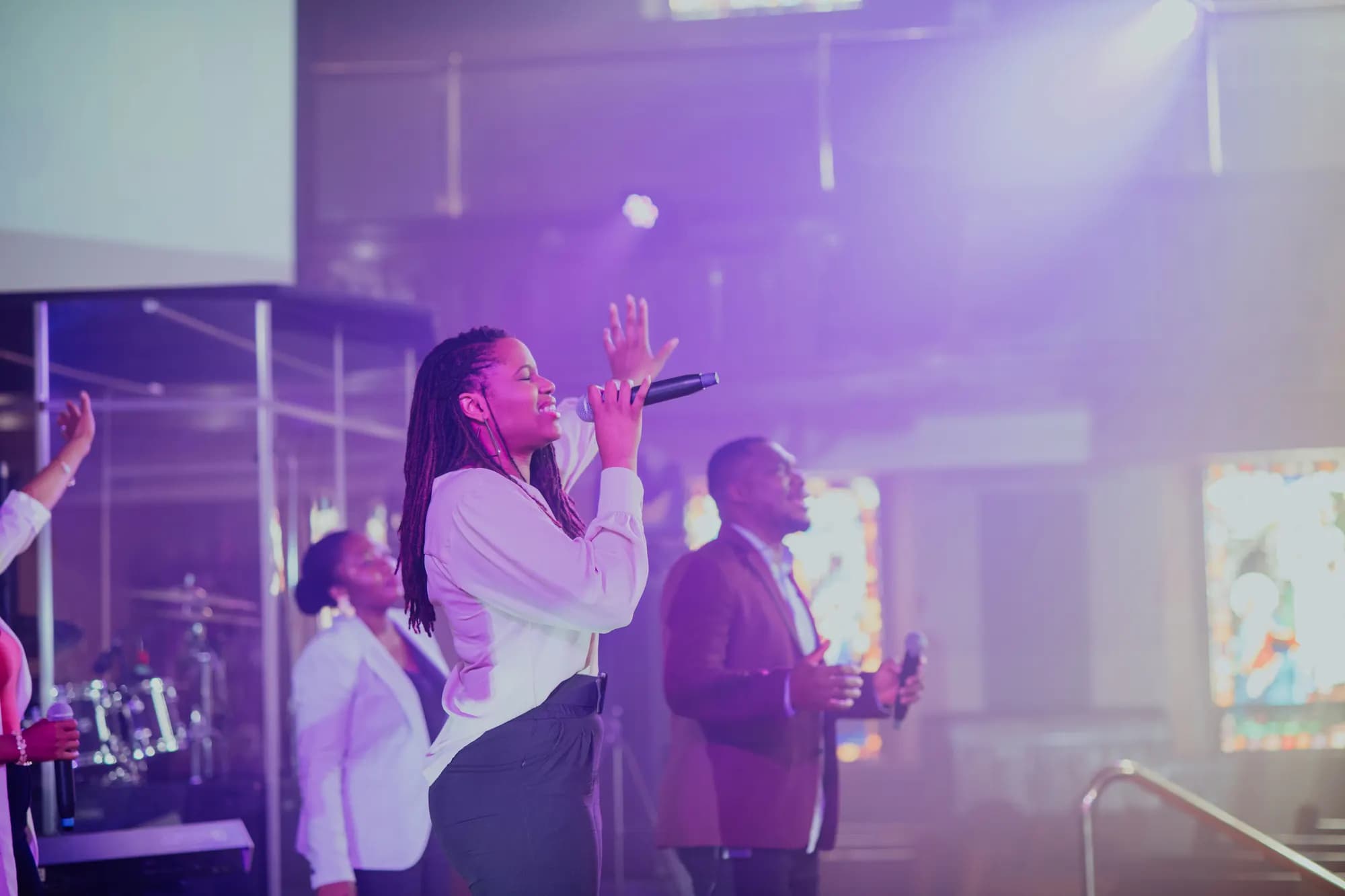 Maxwell AU leading worship alongside a fellow vocalist under stage lights.